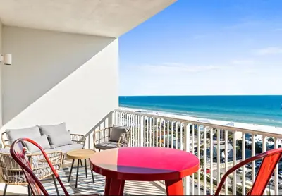 a balcony with a table and chairs and the beach at BeachFrnt 2 Hottub 5 Pools Jet Ski in Panama City Beach