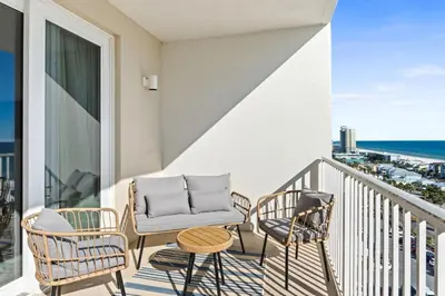 a balcony with chairs and a couch and a view of the ocean at BeachFrnt 2 Hottub 5 Pools Jet Ski in Panama City Beach