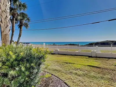 a fence with palm trees and the ocean in the background at Lion On The Beach in Panama City Beach