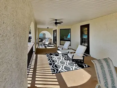 a porch with white chairs and a ceiling fan at Lion On The Beach in Panama City Beach