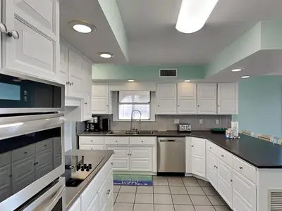 a kitchen with white cabinets and black counter tops at Lion On The Beach in Panama City Beach