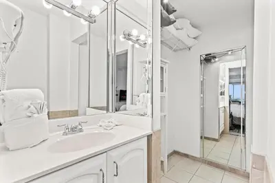 a white bathroom with a sink and a mirror at The Summit 301 in Panama City Beach