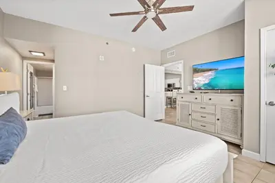 a white bedroom with a bed and a flat screen tv at Spacious 2-Bedroom Condo Beachfront Resort! By Dolce Vita Getaways PCB! in Panama City Beach
