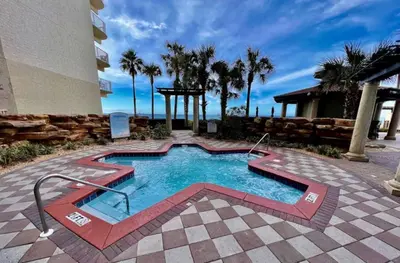 a swimming pool in front of a building with palm trees at Spacious 2-Bedroom Condo Beachfront Resort! By Dolce Vita Getaways PCB! in Panama City Beach