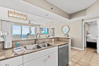 a kitchen with a sink and a view of a bedroom at Spacious 2-Bedroom Condo Beachfront Resort! By Dolce Vita Getaways PCB! in Panama City Beach