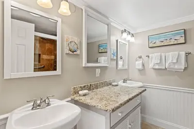 a white bathroom with two sinks and a mirror at Pinnacle Port B3-706 in Panama City Beach