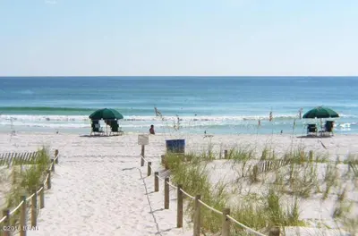 a sandy beach with green umbrellas and the ocean at Pinnacle Port B3-706 in Panama City Beach