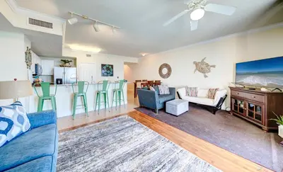 a living room with a blue couch and a kitchen at Stunning Beach front condo in Panama City Beach