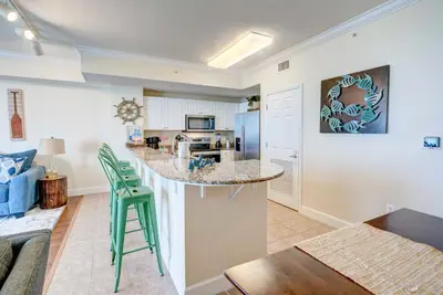a kitchen and living room with a counter and chairs at Stunning Beach front condo in Panama City Beach