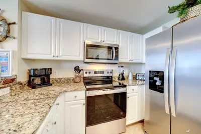 a kitchen with white cabinets and a stainless steel refrigerator at Stunning Beach front condo in Panama City Beach