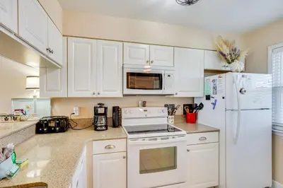 a kitchen with white cabinets and a white refrigerator at Steps to Sand PCB Condo with Gulf-View Balconies! in Panama City Beach