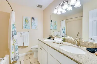 a bathroom with a sink and a toilet and a mirror at Steps to Sand PCB Condo with Gulf-View Balconies! in Panama City Beach