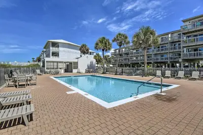 a swimming pool with chairs and a building at Steps to Sand PCB Condo with Gulf-View Balconies! in Panama City Beach