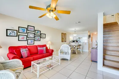 a living room with a red couch and a table at Steps to Sand PCB Condo with Gulf-View Balconies! in Panama City Beach