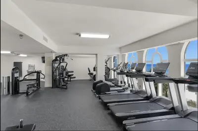 a gym with a row of treadmills and machines at Calypso Resort By Sand Seeker Vacations in Panama City Beach