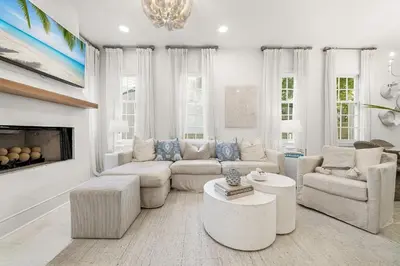 a living room with white furniture and a fireplace at Hazel's Cottage and Carriage House in Rosemary Beach
