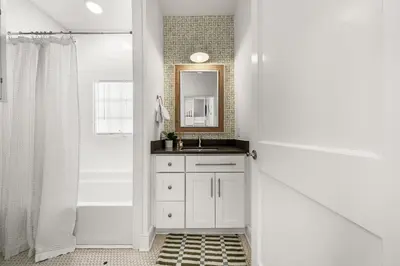 a white bathroom with a sink and a mirror at Hazel's Cottage and Carriage House in Rosemary Beach