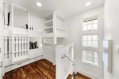 a white hallway with white shelves and a window at Hazel's Cottage and Carriage House in Rosemary Beach