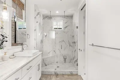 a white bathroom with a shower and a sink at Hazel's Cottage and Carriage House in Rosemary Beach