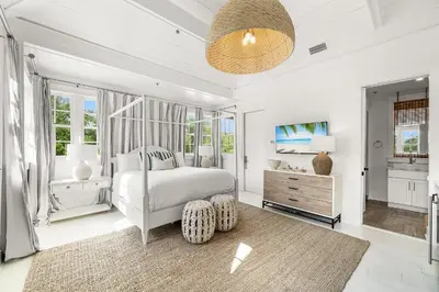 a white bedroom with a bed and a dresser at Hazel's Cottage and Carriage House in Rosemary Beach