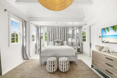 a bedroom with a bed and a tv and windows at Hazel's Cottage and Carriage House in Rosemary Beach
