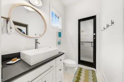 a white bathroom with a sink and a mirror at Hazel's Cottage and Carriage House in Rosemary Beach