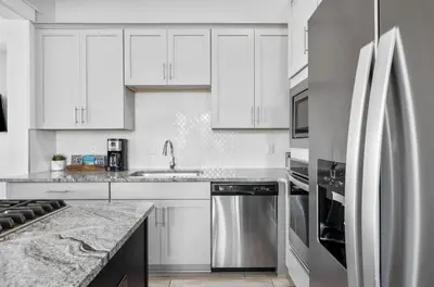 a kitchen with white cabinets and a stainless steel refrigerator at Available for Spring Break! Seas The Day at Inlet Beach in Inlet Beach
