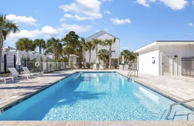 a swimming pool with blue water in a yard at Available for Spring Break! Seas The Day at Inlet Beach in Inlet Beach