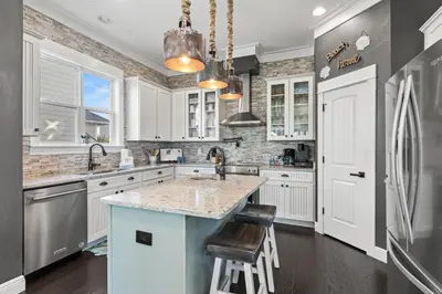 a kitchen with white cabinets and a blue island at Blue Sky Bungalow in Inlet Beach