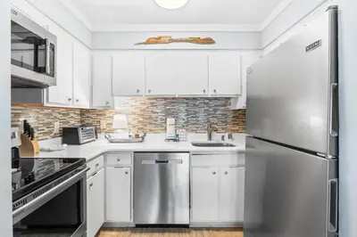 a kitchen with white cabinets and a stainless steel refrigerator at Endless Summer A36 - 