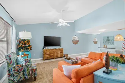 a living room with orange furniture and a christmas tree at Beach House - Paradise Palace by Panhandle Getaways in Panama City Beach