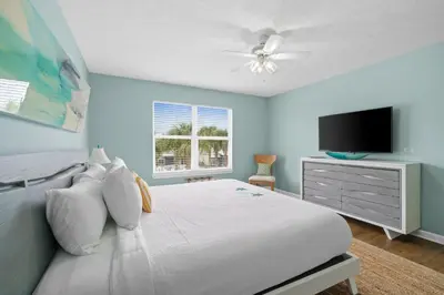 a bedroom with a white bed and a flat screen tv at Beach House - Paradise Palace by Panhandle Getaways in Panama City Beach