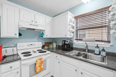 a kitchen with white cabinets and a sink at Beach House - Paradise Palace by Panhandle Getaways in Panama City Beach