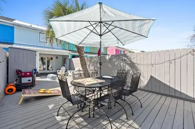 a table and chairs with an umbrella on a deck at Pet-friendly condo, less than 5 min walk to beach, beach chairs, wagon, umbrella etc. included! in Panama City Beach