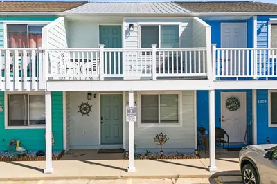 a blue and white house with a balcony at Pet-friendly condo, less than 5 min walk to beach, beach chairs, wagon, umbrella etc. included! in Panama City Beach