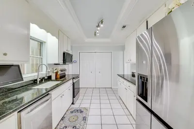 a kitchen with white cabinets and a refrigerator at Boat Dock and Game Room Waterfront Panama City Gem in Lynn Haven