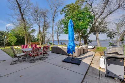 a patio with a table and chairs and an umbrella at Boat Dock and Game Room Waterfront Panama City Gem in Lynn Haven