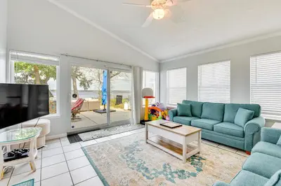 a living room with a blue couch and a tv at Boat Dock and Game Room Waterfront Panama City Gem in Lynn Haven