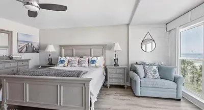 a bedroom with a bed and a chair and a window at Ocean Bliss by Emerald Coast Retreats in Panama City Beach