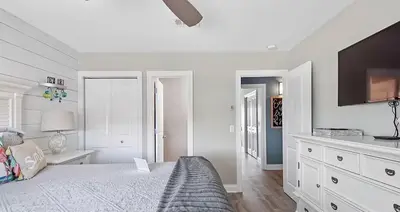a white bedroom with a bed and a flat screen tv at Ocean Bliss by Emerald Coast Retreats in Panama City Beach