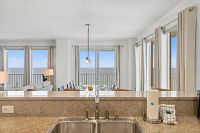 a kitchen and living room with a view of the ocean at Treasure Shores–3BR Beachfront Corner Unit sleeps 8 with Stunning Gulf Views! in Panama City Beach