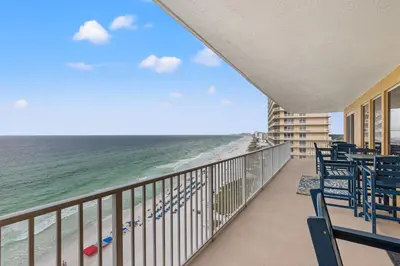 a balcony with chairs and a view of the ocean at Treasure Shores–3BR Beachfront Corner Unit sleeps 8 with Stunning Gulf Views! in Panama City Beach