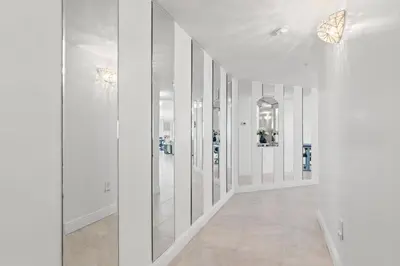 a hallway with white walls and mirrors and butterflies on the walls at Treasure Shores–3BR Beachfront Corner Unit sleeps 8 with Stunning Gulf Views! in Panama City Beach