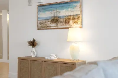 a table with a lamp and a painting on the wall at Treasure Shores–3BR Beachfront Corner Unit sleeps 8 with Stunning Gulf Views! in Panama City Beach