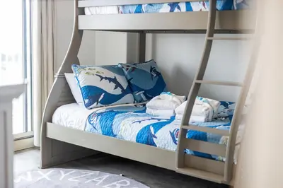 a childs bunk bed with blue and white bedding at Treasure Tides–3BR Beachfront Corner Unit sleeps 8 with Stunning Gulf Views! in Panama City Beach