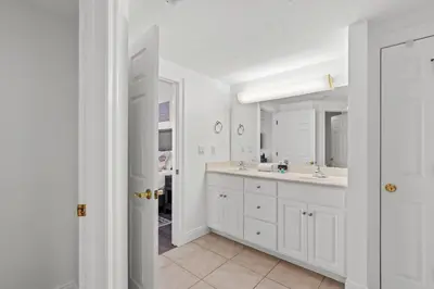 a white bathroom with two sinks and a mirror at Treasure Tides–3BR Beachfront Corner Unit sleeps 8 with Stunning Gulf Views! in Panama City Beach