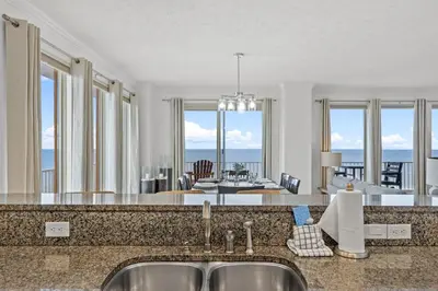 a kitchen and living room with a view of the ocean at Treasure Tides–3BR Beachfront Corner Unit sleeps 8 with Stunning Gulf Views! in Panama City Beach