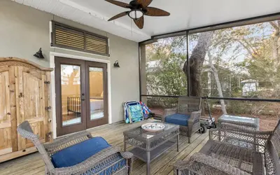 a screened in porch with chairs and a ceiling fan at Sea Stars by Oversee 30A in Seacrest