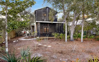 a glass house in the woods with trees at Sea Stars by Oversee 30A in Seacrest