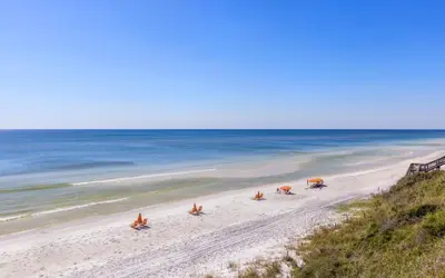 a beach with people sitting on the sand and the ocean at Sea Stars by Oversee 30A in Seacrest